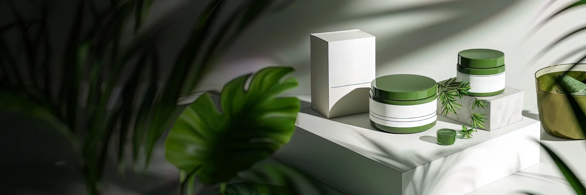 Skincare products in green and white containers displayed with leaves and natural light. Elegant design suggesting a botanical theme.